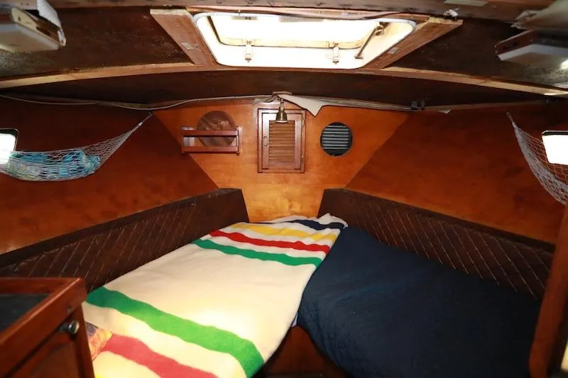 Slide: The Image of 1972 Trojan 36 boat cabin interior with cozy bedding and wooden paneling. - 17