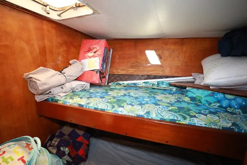 Slide: The Image of 1972 Trojan 36 boat cabin with wooden interior and floral bedding. - 19
