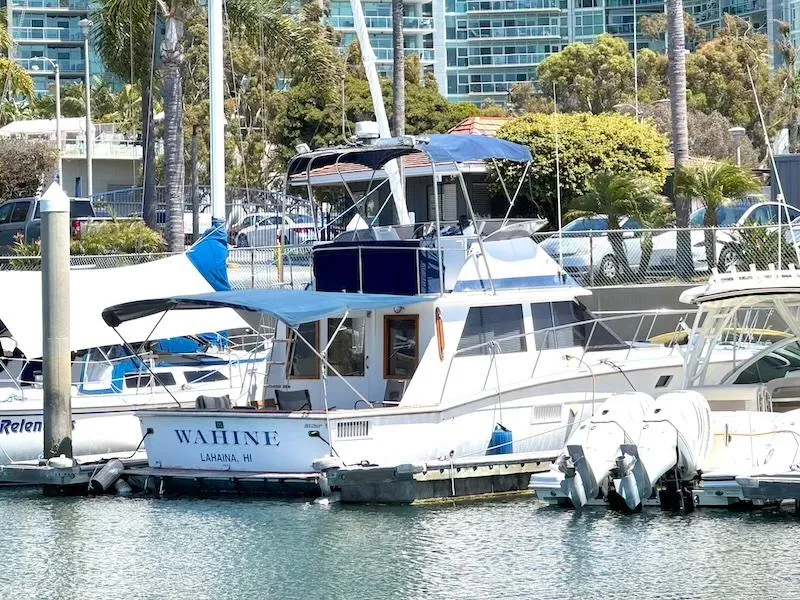 Slide: The Image of 1972 Trojan 36 boat docked in marina, surrounded by other vessels and palm trees. - 2