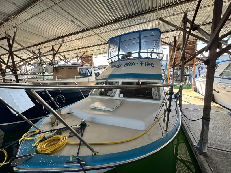 The Image of 1974 Roberts 30' boat docked in a covered marina, featuring a blue and white design. - 0