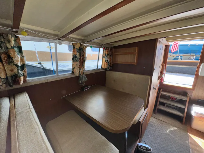 Slide: The Image of 1974 Roberts 30' boat interior with dining area, floral curtains, and wooden table. - 24