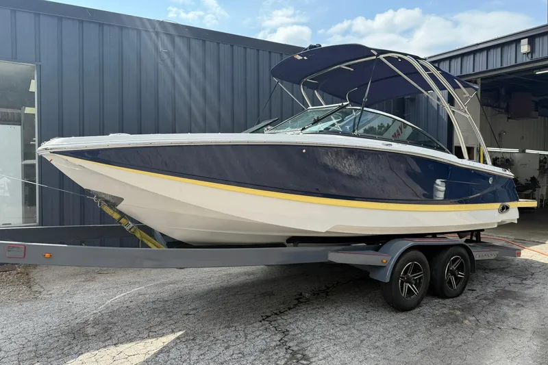 Slide: The Image of 2009 Four Winns SL222 boat on trailer, parked outside a metal building. - 1