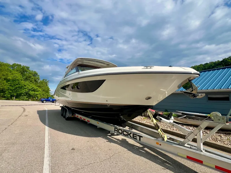 Slide: The Image of 2019 Sea Ray SLX 400 boat on trailer, parked outdoors under cloudy sky. - 2