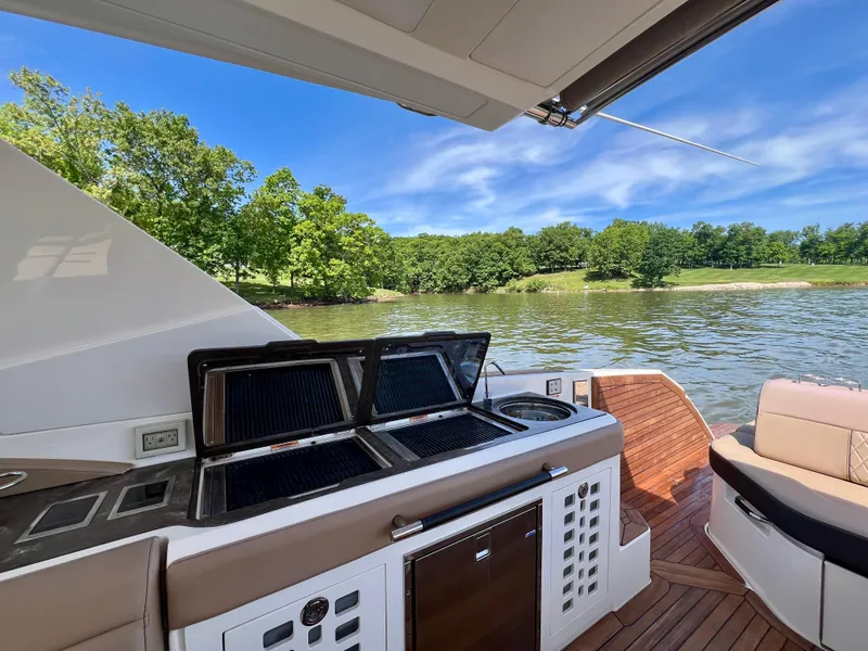 Slide: The Image of 2019 Sea Ray SLX 400 boat with outdoor kitchen, scenic lake view, and lush greenery. - 20