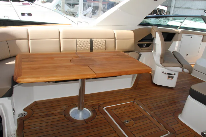 Slide: The Image of 2019 Sea Ray SLX 400 interior with wooden table and beige seating. - 23