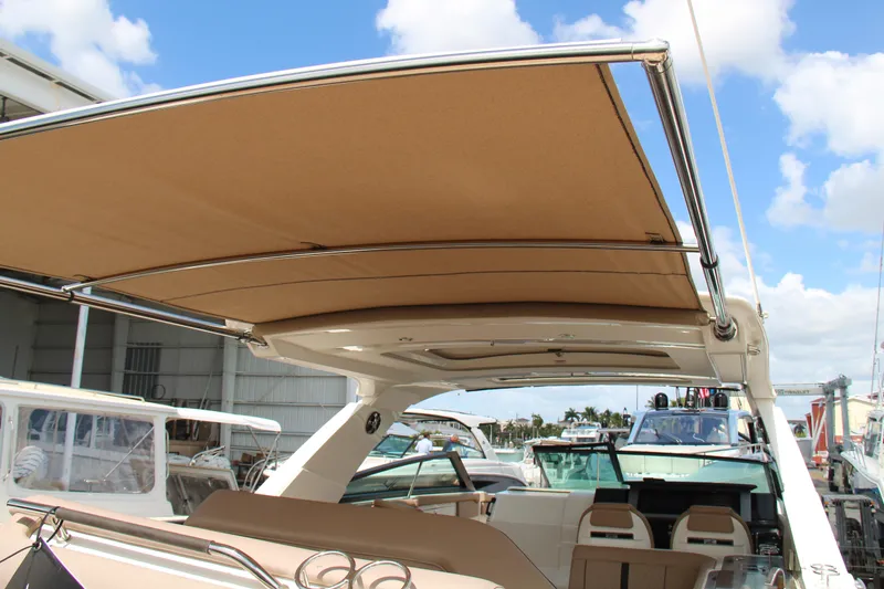 Slide: The Image of 2019 Sea Ray SLX 400 boat with tan canopy, docked under blue sky. - 24