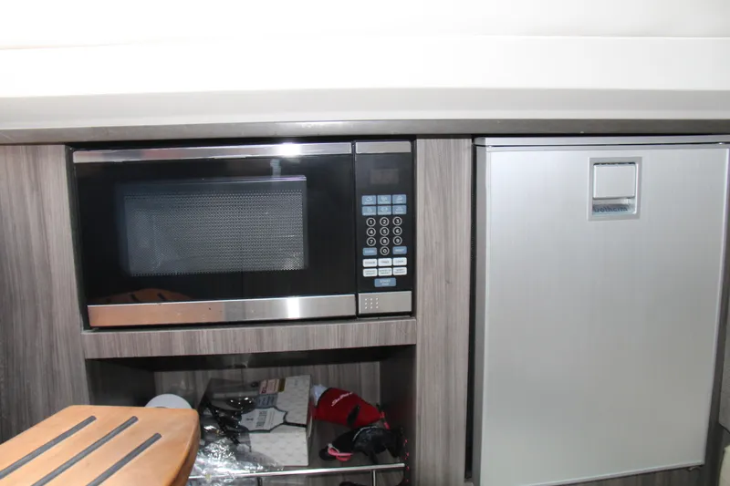 Slide: The Image of 2019 Sea Ray SLX 400 interior with microwave and mini fridge in modern kitchen area. - 32