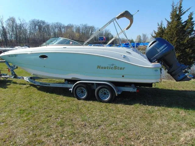 Slide: The Image of 2019 NauticStar 243 DC boat on trailer, parked on grass, with Yamaha outboard motor. - 3