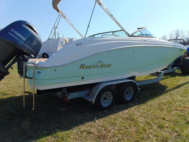 Slide: The Image of 2019 NauticStar 243 DC boat on trailer with Yamaha outboard engine, parked on grass. - 5