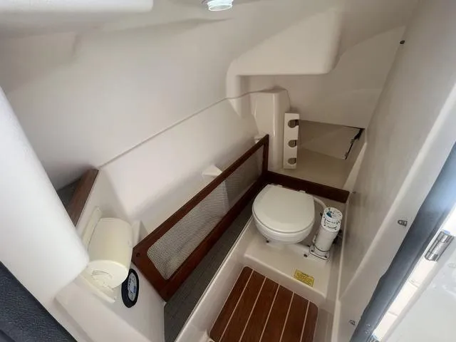 Slide: The Image of 2016 Grady-White Freedom 275 boat interior with compact marine toilet and wooden flooring. - 11