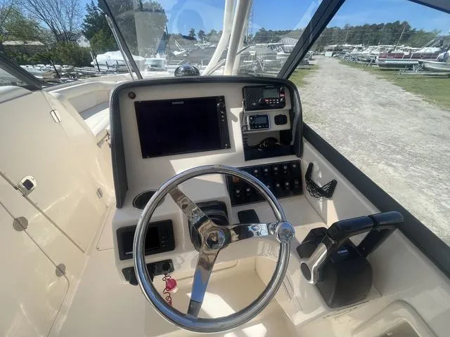 Slide: The Image of 2016 Grady-White Freedom 275 boat dashboard with steering wheel and navigation controls. - 9