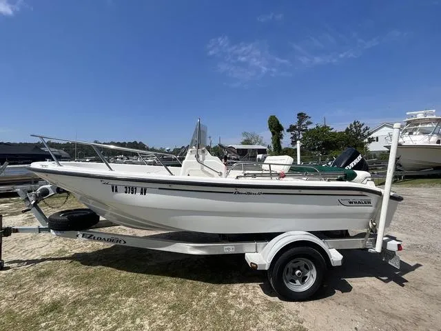 Slide: The Image of 1999 Boston Whaler 160 Dauntless boat on trailer, parked outdoors under clear blue sky. - 3