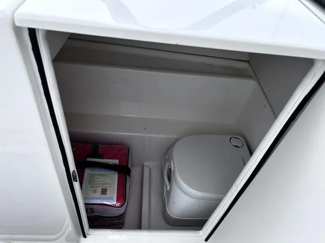 Slide: The Image of 2021 Bayliner VR6 Bowrider storage compartment with portable toilet and safety equipment. - 14