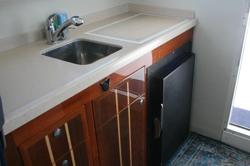 Slide: The Image of Compact kitchen area in a 2011 Ocean Sport Roamer 30' boat, featuring a sink and cabinetry. - 11