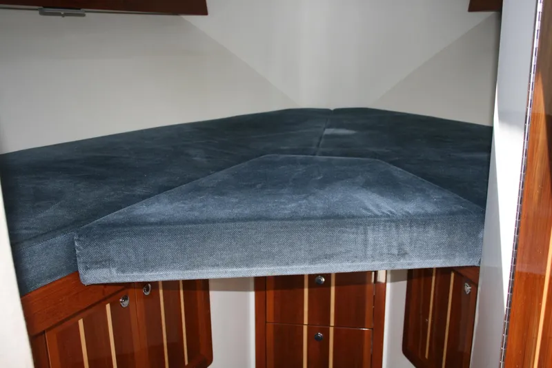 Slide: The Image of Interior cabin of 2011 Ocean Sport Roamer 30', featuring a cozy V-berth with blue upholstery. - 13