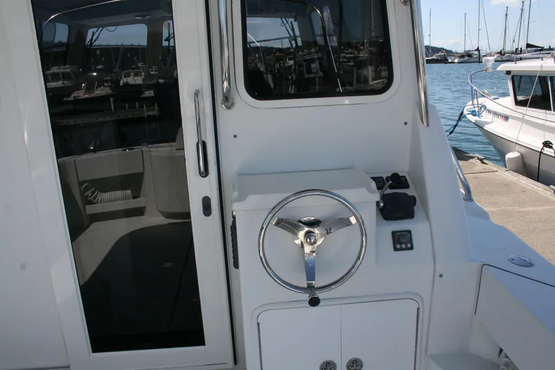 Slide: The Image of 2011 Ocean Sport Roamer 30' boat helm with steering wheel and controls, docked at marina. - 2