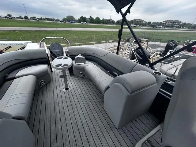 Slide: The Image of 2020 Lowe SS250 WS WindShield boat interior with gray seating and table, parked outdoors. - 12