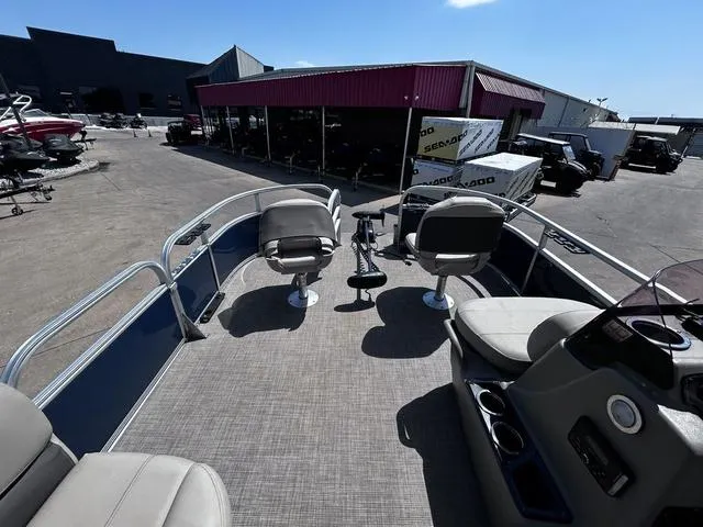 Slide: The Image of 2023 Sun Tracker Bass Buggy® 16 XL Select pontoon boat with seating, parked at a dealership. - 13