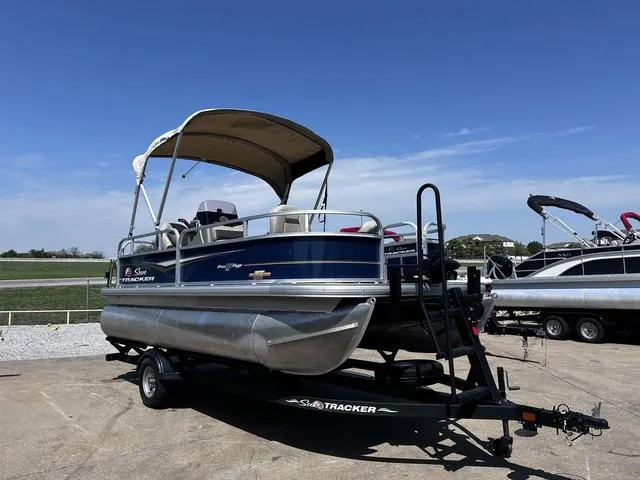 Slide: The Image of 2023 Sun Tracker Bass Buggy® 16 XL Select pontoon boat on trailer, under clear blue sky. - 4