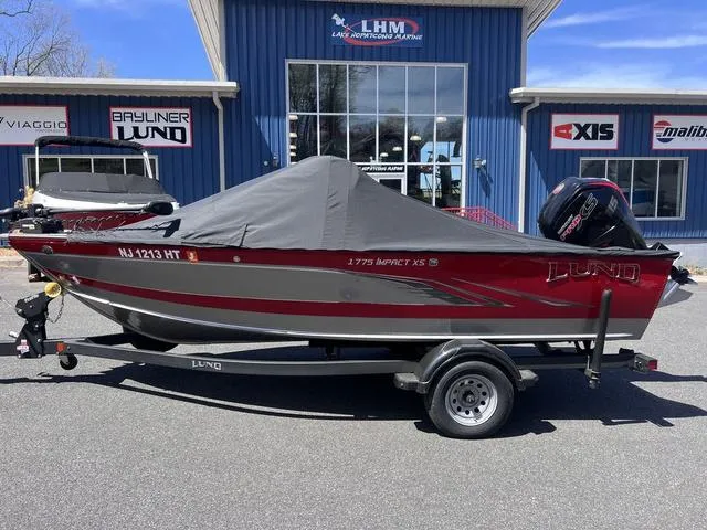 Slide: The Image of 2023 Lund 1775 Impact XS Sport boat on trailer, covered, outside dealership. - 10