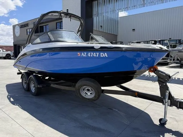Slide: The Image of 2017 Yamaha AR210 boat on trailer, blue and black, parked outdoors. - 2