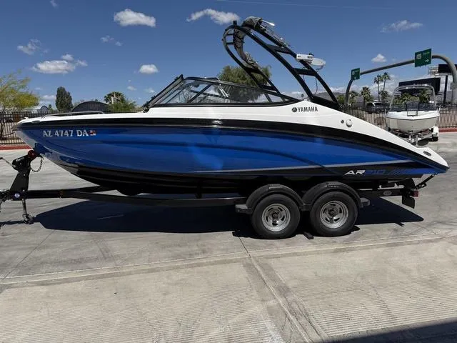 Slide: The Image of 2017 Yamaha AR210 boat on trailer, blue and white design, parked outdoors. - 5