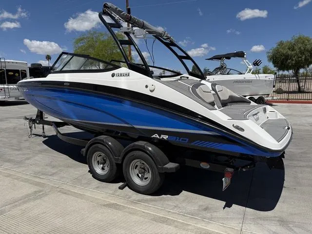 Slide: The Image of 2017 Yamaha AR210 boat on trailer, blue and white design, parked outdoors under clear sky. - 6