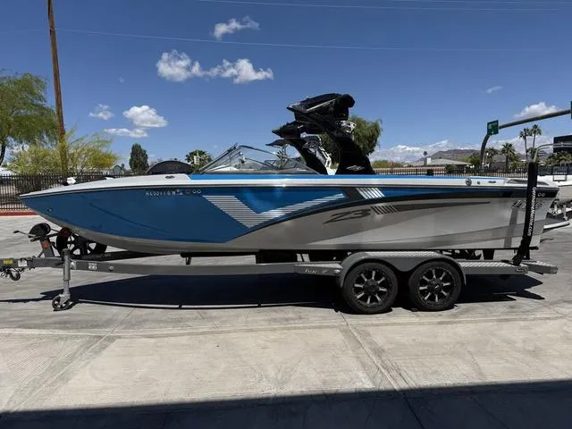 Slide: The Image of 2015 Tigé Z3 boat on trailer, blue and white, parked outdoors under clear sky. - 5