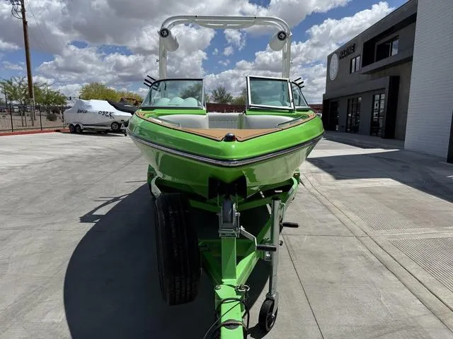 Slide: The Image of Green 2016 Sanger 215S boat on trailer, parked outdoors under a cloudy sky. - 3
