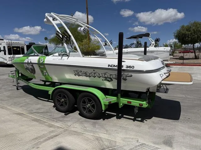 Slide: The Image of 2016 Sanger 215S boat on a green trailer, parked outdoors under a blue sky. - 6