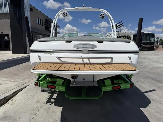 Slide: The Image of 2016 Sanger 215S boat, rear view, white with green accents, parked outdoors. - 7