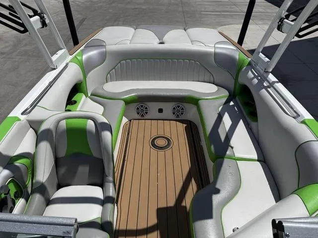 Slide: The Image of 2016 Sanger 215S boat interior with green and white seating, wood flooring, and speakers. - 8
