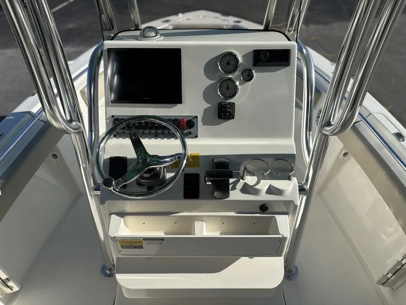 Slide: The Image of 2025 Key West 219 FS boat console with steering wheel, gauges, and storage compartments. - 12