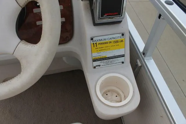 Slide: The Image of 2002 Harris Cruiser 200 boat dashboard with capacity label and cup holder. - 10