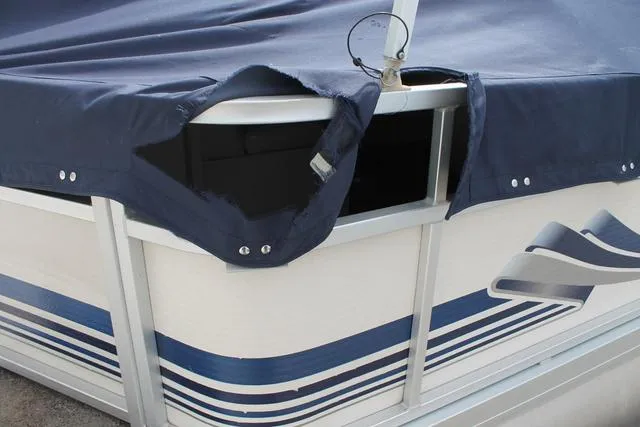 Slide: The Image of 2002 Harris Cruiser 200 boat with torn blue cover and visible interior. - 3