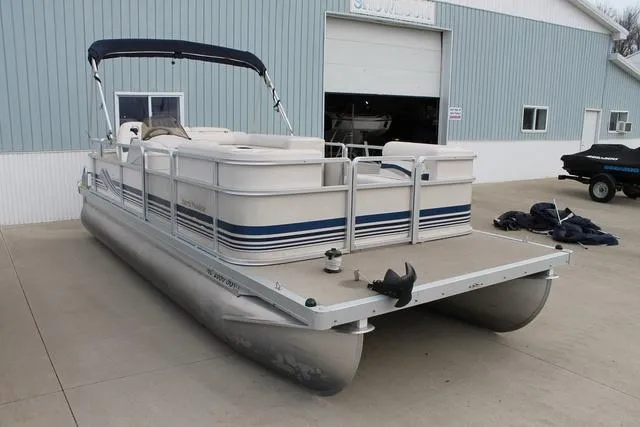 Slide: The Image of 2002 Harris Cruiser 200 pontoon boat parked outside a garage. - 5