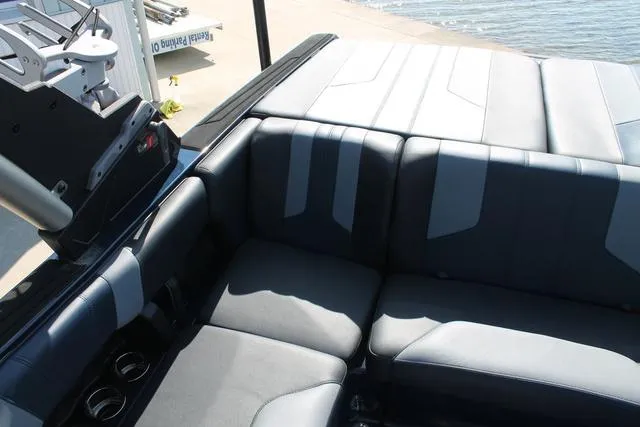 Slide: The Image of 2023 Malibu 21 LX boat interior with sleek, modern seating near the water. - 10