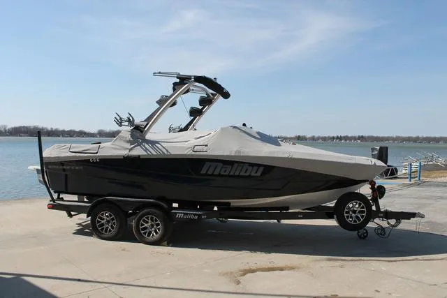 Slide: The Image of 2023 Malibu 21 LX boat on trailer by the waterfront, covered and ready for transport. - 5