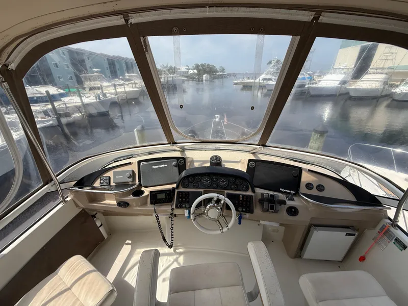 Slide: The Image of 2005 Carver 41 Cockpit Motor Yacht helm with marina view, featuring modern navigation equipment. - 13