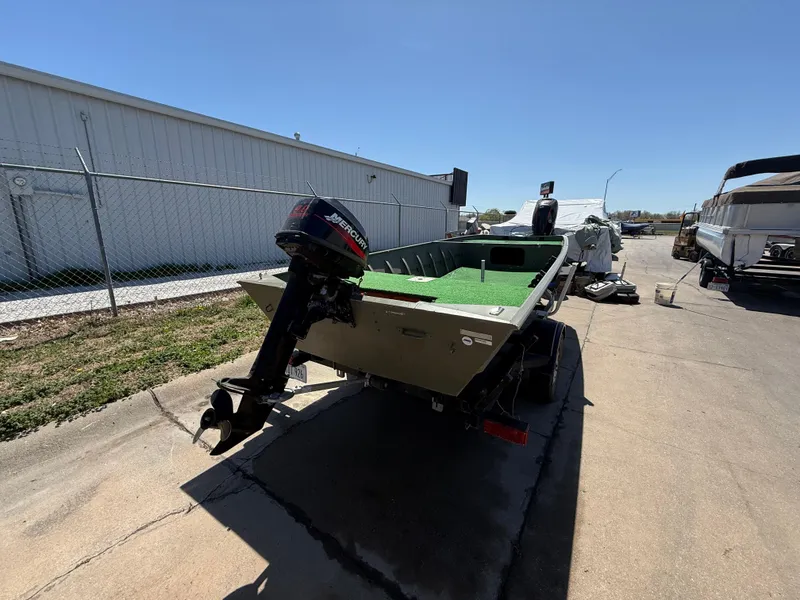 Slide: The Image of 2002 Tracker Grizzly 1648 boat with outboard motor, parked outdoors on a sunny day. - 4