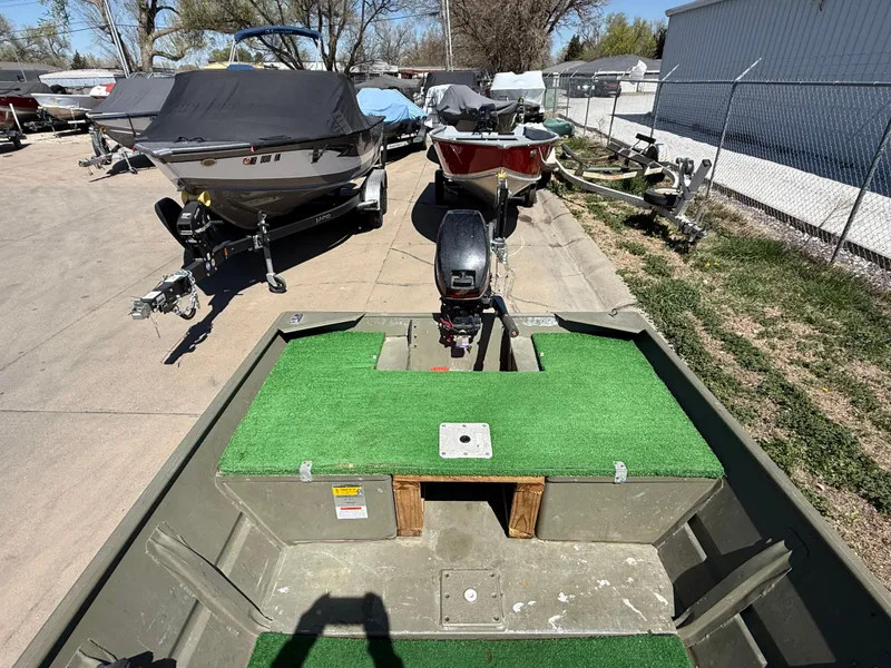 Slide: The Image of 2002 Tracker Grizzly 1648 boat with green deck, parked among other boats. - 6