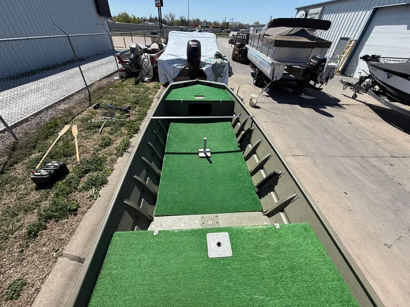 Slide: The Image of 2002 Tracker Grizzly 1648 boat with green carpeted interior, parked outdoors. - 8