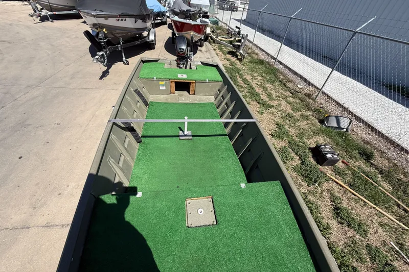 Slide: The Image of 2002 Tracker Grizzly 1648 boat with green carpeted interior, parked on concrete. - 9