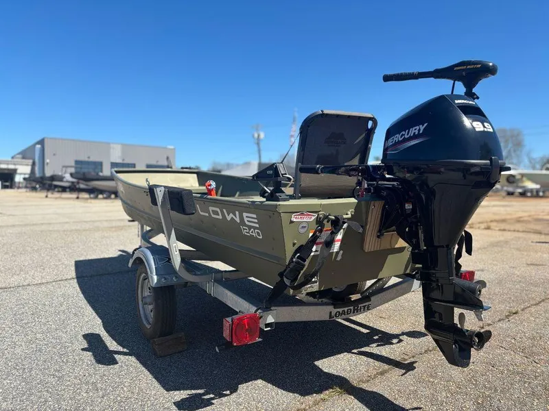 Slide: The Image of 2024 Lowe L1240 Jon boat with Mercury engine on trailer, parked outdoors. - 2