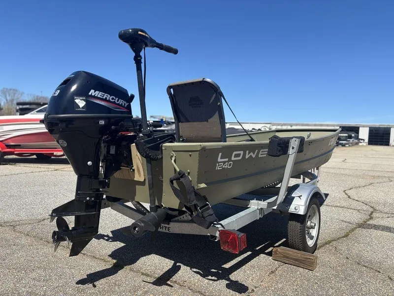 Slide: The Image of 2024 Lowe L1240 Jon boat with Mercury motor on trailer, parked outdoors. - 5