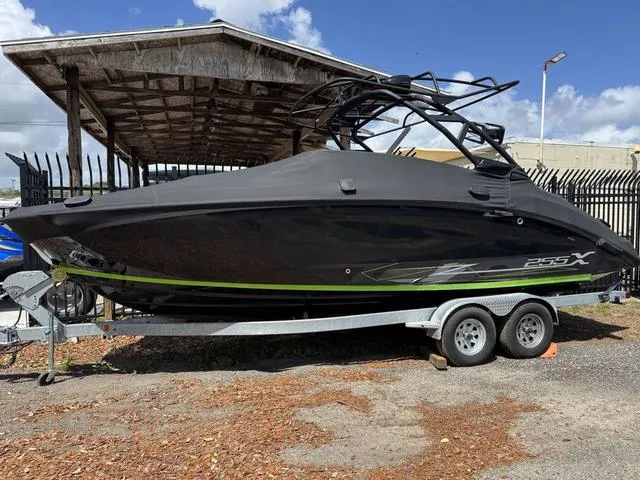 Slide: The Image of 2021 Yamaha Boats 255XD on trailer, black with green accents, parked outdoors. - 1
