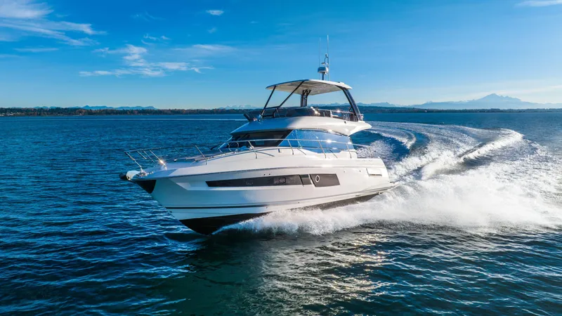 Slide: The Image of 2024 Prestige 460 Fly yacht cruising on open water under clear blue skies. - 2