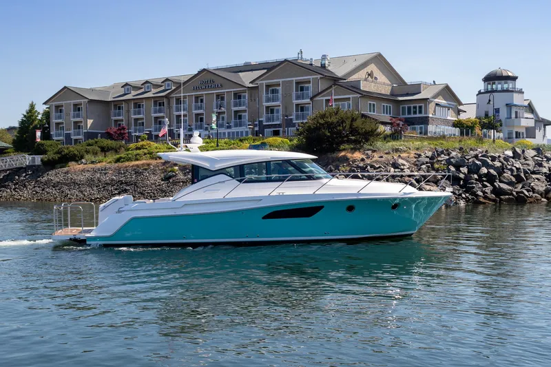 The Image of 2023 Tiara Yachts C44 Coupe cruising near a coastal hotel. - 0