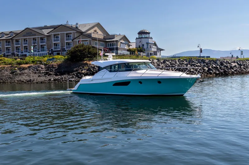 Slide: The Image of 2023 Tiara Yachts C44 Coupe cruising near waterfront buildings. - 1