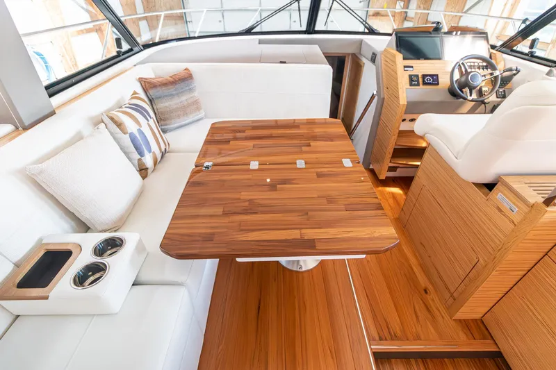 Slide: The Image of 2023 Tiara Yachts C44 Coupe interior with wooden table, white seating, and helm station. - 15